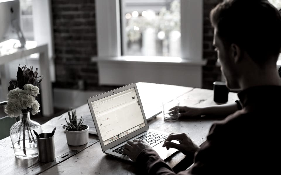 Someone writing at a laptop beside a window