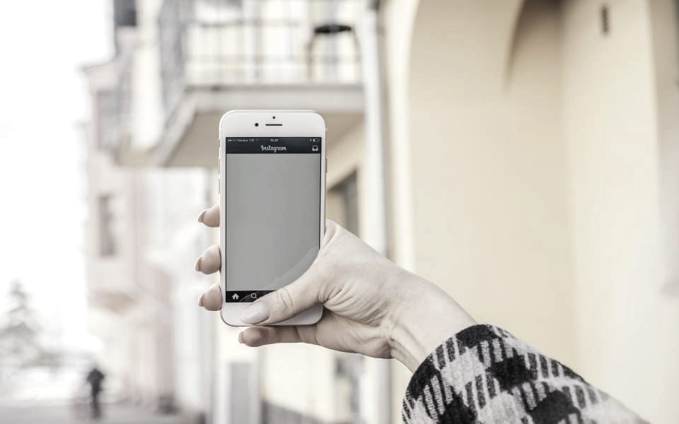 A hand holding a phone open on a social feed in the street